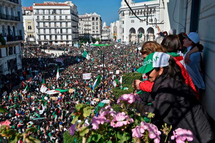 Algerians look down from a balcony upon protesters gathering during a mass demonstration against ailing President Abdelaziz Bouteflika in the capital Algiers on March 29, 2019. Opposition to Bouteflika has been widening since the chief of staff, General Ahmed Gaid Salah on March 26, 2019 invoked Article 102 of the constitution under which a president can be removed if found unfit to rule. / AFP / RYAD KRAMDI